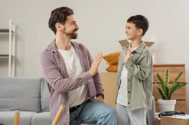 Baba ve küçük oğlu taşınma günü mobilya montajı yaparken birbirlerine beşlik çakıyorlar.