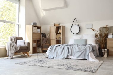 Koltuğu ve aynası olan rahat, modern bir yatak odası.