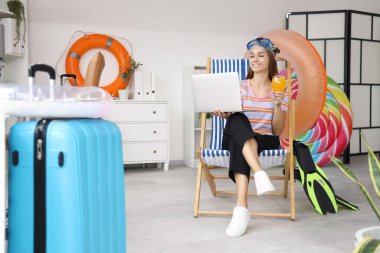 Kokteyl ve dizüstü bilgisayarlı genç iş kadını yaz tatilini ofiste bekliyor.