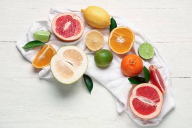 Beyaz ahşap zemin üzerinde peçete ve lezzetli narenciye meyveleri