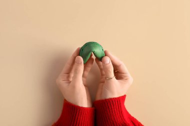 Bej arka planda yeşil fal kurabiyesi olan kadın elleri