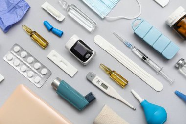 Nabız oksimetresi, termometre, şırınga, astım spreyi ve beyaz zemin üzerindeki ilaçlarla bileşim