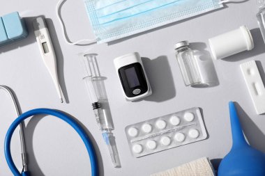 Beyaz arka planda nabız oksimetresi, termometre, şırınga ve ilaçlarla bileşim