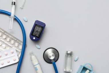 Beyaz arka planda nabız oksimetresi, steteskop ve ilaçlarla bileşim
