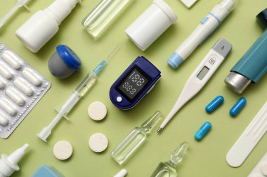 Yeşil arka planda nabız oksimetresi, şırınga ve ilaç bileşimi, yakın plan.