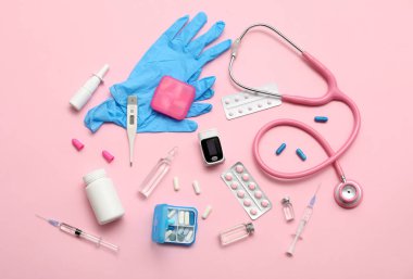 Nabız oksimetresi, şırınga, steteskop ve pembe arka plandaki ilaçlarla bileşim