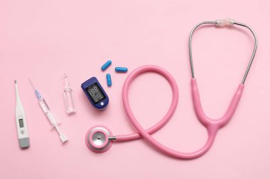 Pembe arka planda nabız oksimetresi, steteskop, hap, şırınga, termometre ve ampul bileşimi