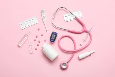 Pembe arka planda nabız oksimetresi, steteskop ve ilaçlı bileşim