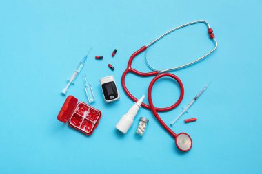 Mavi arka planda nabız oksimetresi, steteskop ve ilaçlı bileşim
