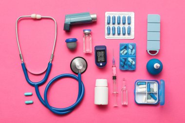 Nabız oksimetresi, şırınga, steteskop ve pembe arka plandaki ilaçlarla bileşim