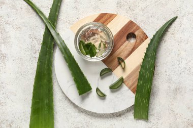 Tahta tepsi, taze aloe jeli kase ve beyaz grunge arka planda yapraklar.