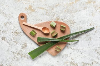 Ahşap kesme tahtası ve beyaz grunge arka planda taze aloe vera yaprakları ile kaşık