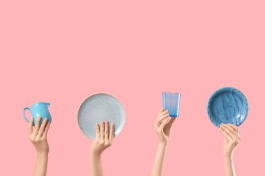 Pembe arka planda tabak, sürahi ve cam kaplı kadın elleri.