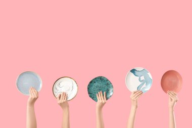 Pembe arka planda farklı plakalı kadın elleri