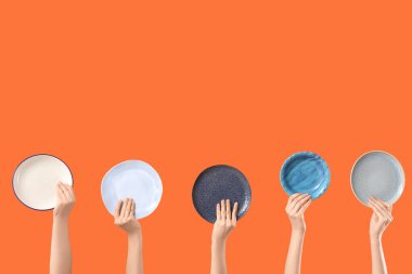 Turuncu arka planda farklı plakalı kadın elleri.