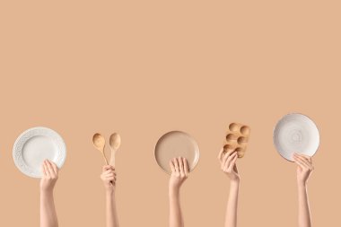 Tabaklı kadın elleri, tahta yumurta tutacağı ve bej arka planda kaşıklar.