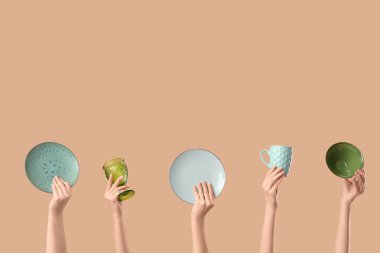 Plakası, kasesi, kupası ve bej arka planı olan kadın elleri.