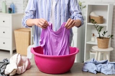 Genç bir kadın evdeki plastik havuzda çamaşır yıkıyor.