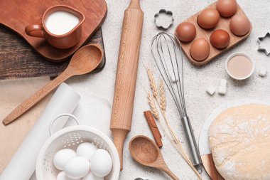 Ahşap oklamalı kompozisyon, hamur malzemeleri ve gri grunge arka planda farklı mutfak aletleri.