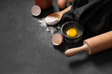 Koyu arkaplanda hamur için ahşap raptiye, peçete ve malzeme içeren kompozisyon