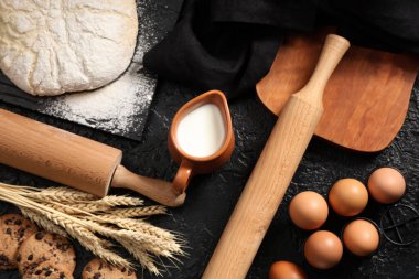 Siyah arka planda hamur için ahşap oklamalı kompozisyon ve malzemeler, yakın plan