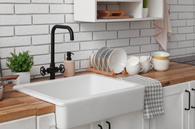 Mutfakta lavabonun yanındaki ahşap tezgahta temiz tabaklar.