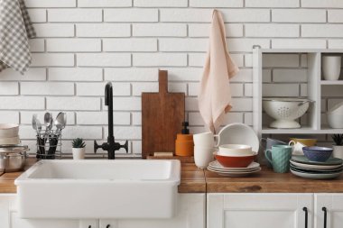 Mutfak tezgahında lavabo, temiz tabaklar ve havlular asılı.