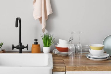 Şık seramik lavabo ve ahşap mutfak tezgahında temiz tabaklar.