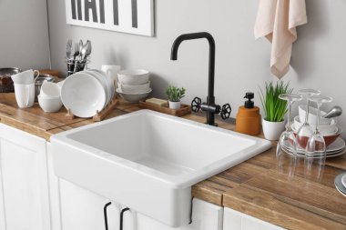 Şık seramik lavabo ve ahşap mutfak tezgahında temiz tabaklar.
