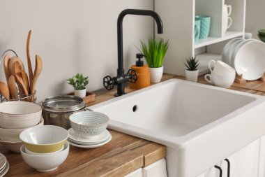 Şık seramik lavabo ve ahşap mutfak tezgahında temiz tabaklar.