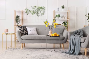 Sehpanın üzerinde vazoda limon dalları, kanepede ve oturma odasının iç kısmında koltuk.