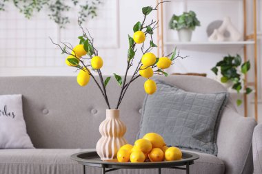 Sehpanın üzerinde vazoda limon dalları, kanepede ve oturma odasının iç kısmında koltuk.