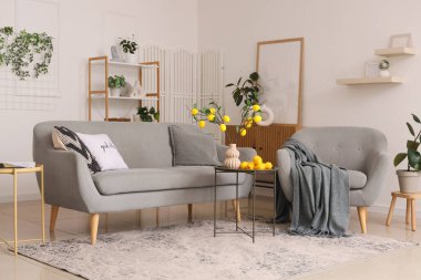 Sehpanın üzerinde vazoda limon dalları, kanepede ve oturma odasının iç kısmında koltuk.