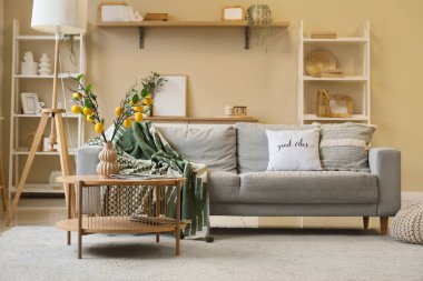 İçinde limon ağacı dalları olan bir sehpa vazo ve oturma odasının içindeki kanepe.