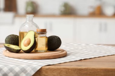 Şişeler dolusu taze yağ ve mutfak masasının üzerinde avokado olan kesme tahtası.