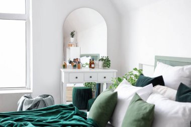 Yatak odasının içinde tuvalet masası ve beyaz duvarın yanında yatak.