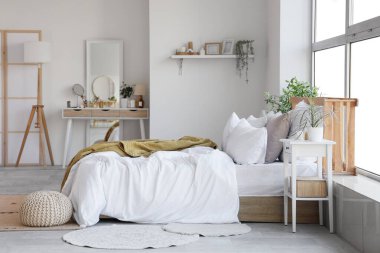 Yatak odasının içinde tuvalet masası ve beyaz duvarın yanında yatak.