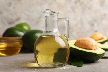 Gri arka planda bir sürahi avokado yağı