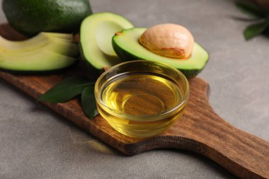 Gri arka planda bir kase avokado yağı