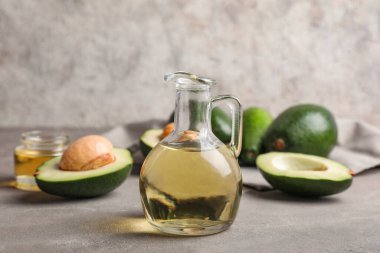 Gri arka planda bir sürahi avokado yağı