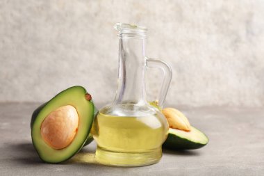 Gri arka planda bir sürahi avokado yağı