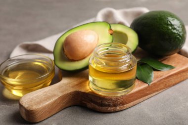 Gri arka planda avokado yağı olan kompozisyon, yakın plan.