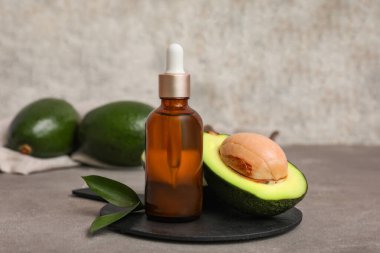 Gri arka planda bir şişe avokado yağı.