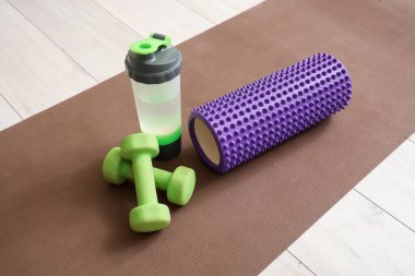 Köpük silindir, bir şişe su ve dambıl. Yakın çekim.