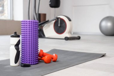 Su şişeli köpük silindirli, halterli ve spor salonundaki paspaslı akıllı, yakın plan.