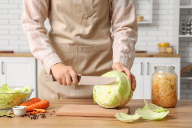 Mutfaktaki masada lahana turşusu için lahana kesen kadın. Yakın çekim.