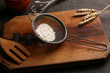 Un, mutfak gereçleri ve arka planda çivili metal elek.