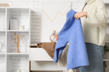 Kadın soyunma odasında kalın kazak katlıyor.