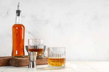 Gri arka planda bir bardak rom, şişe ve jigger. Yakın çekim.