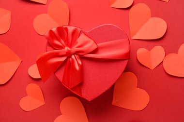 Kırmızı arka planda kağıt kalpler olan hediye kutusu. Sevgililer Günü kutlaması